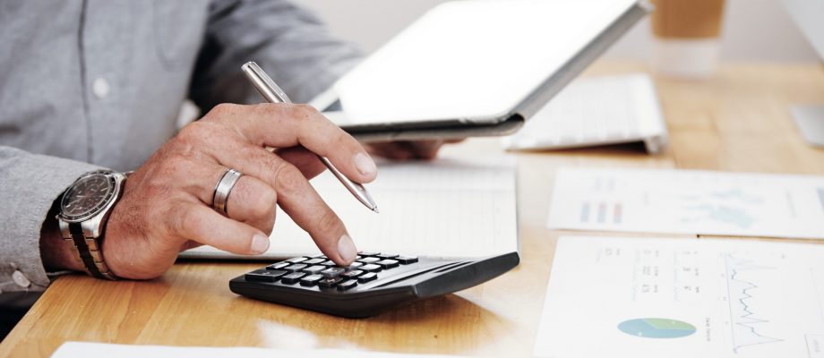 Accounting work at office Close-up of businessman counting the profit of the company and using digital tablet at office desk
