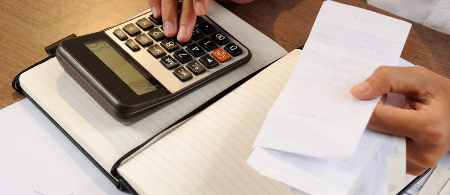 Closeup of woman calculating bills on calculator Closeup of woman calculating bills on calculator. Notebook and calculator lying on desk. Accountancy concept. Cropped view.